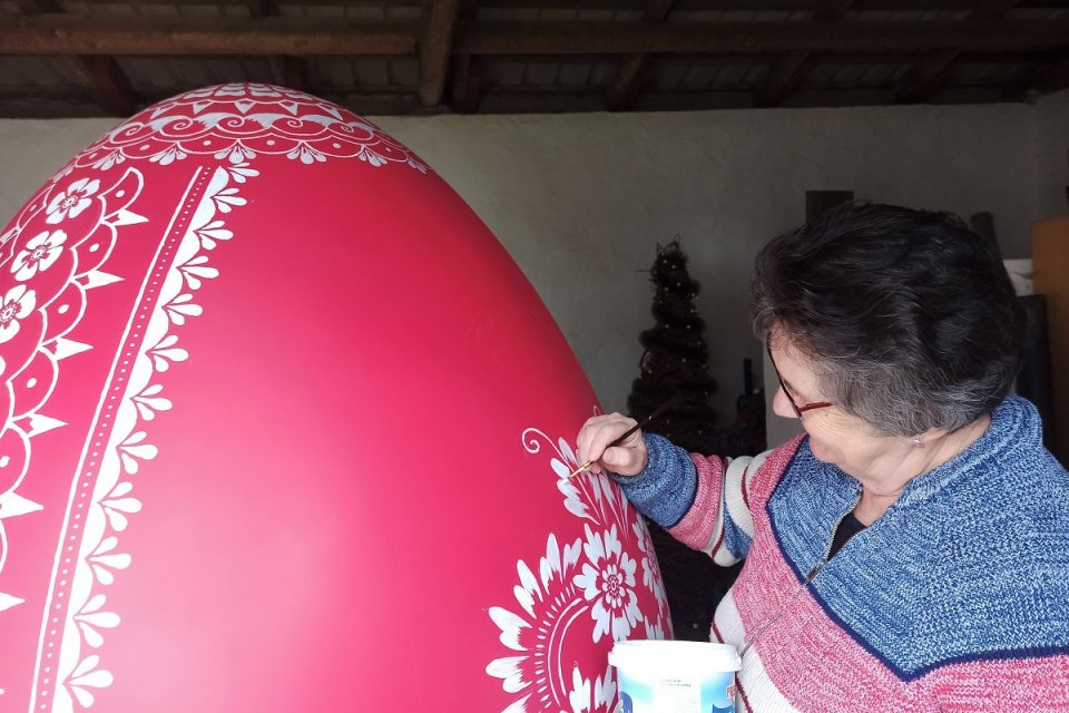 Teresa Sobota maluje ogromne czerwone jajo wzorem opolskim